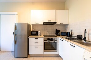 A compact kitchen with a refrigerator, microwave, stove, and coffee maker. - Veta 31 . 1-BR Apt. & Balcony in Larnaca (Larnaca)