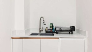 A kitchen with a white countertop, a stainless steel faucet, and a black soap dispenser. - New! Bright 2BR Duplex w/Patio in Pimlico (Greater London)