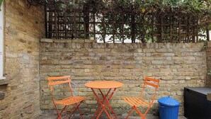 A brick wall with a wooden fence and a small table with two chairs. - New! Bright 2BR Duplex w/Patio in Pimlico (Greater London)