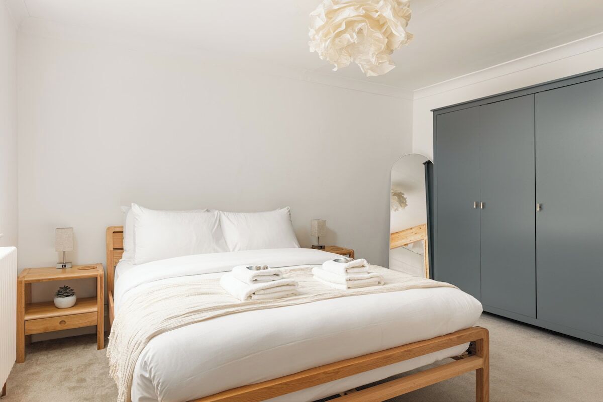 A bedroom with a bed, nightstands, a wardrobe, and a hanging light fixture.