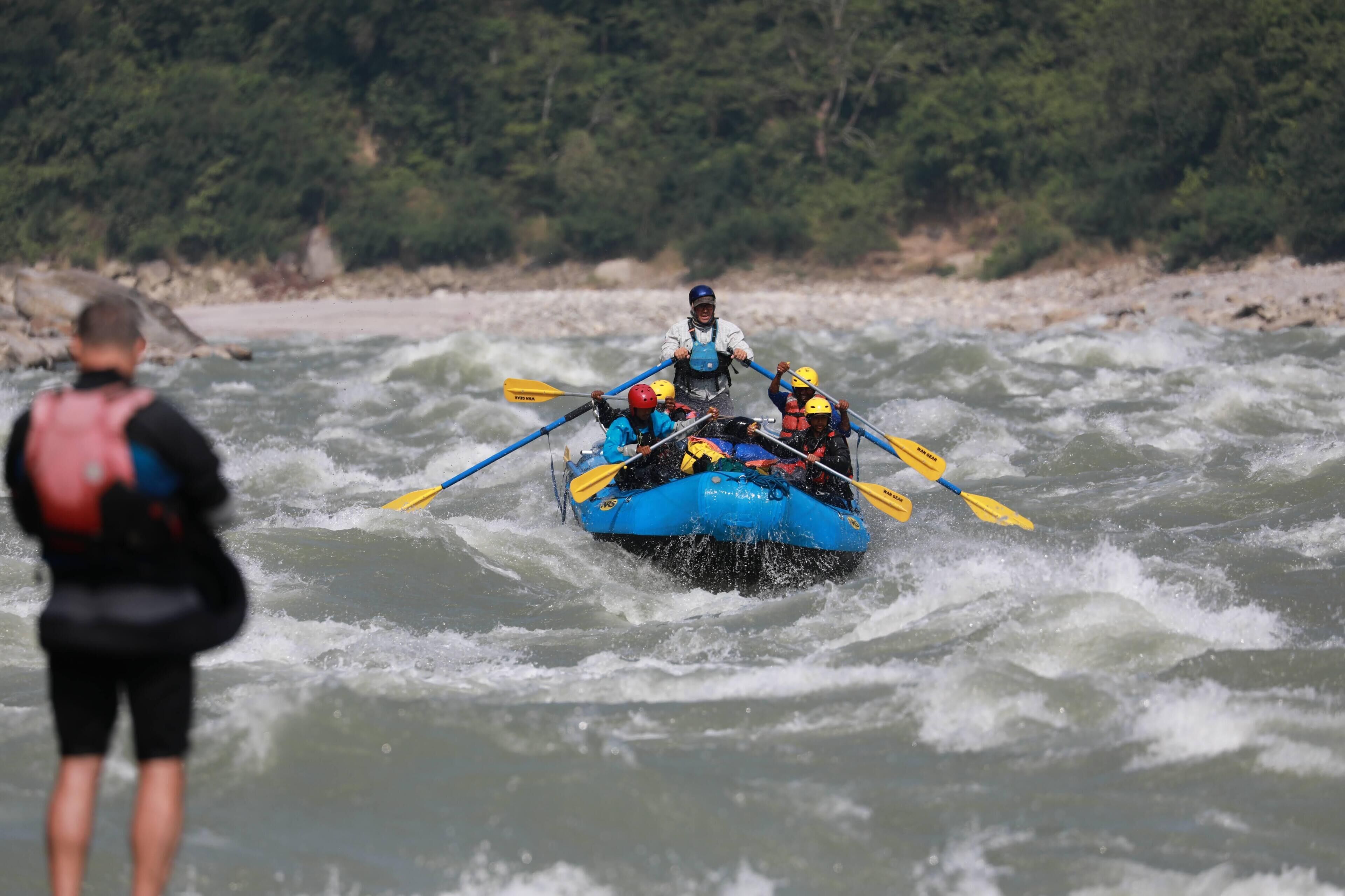 A group of people in a blue raft navigating through a river.