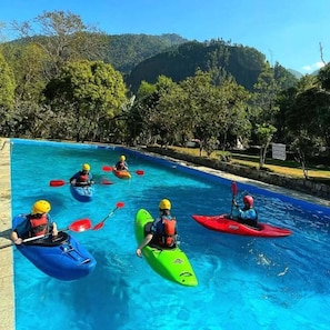 A group of people kayaking in a pool surrounded by trees and hills.