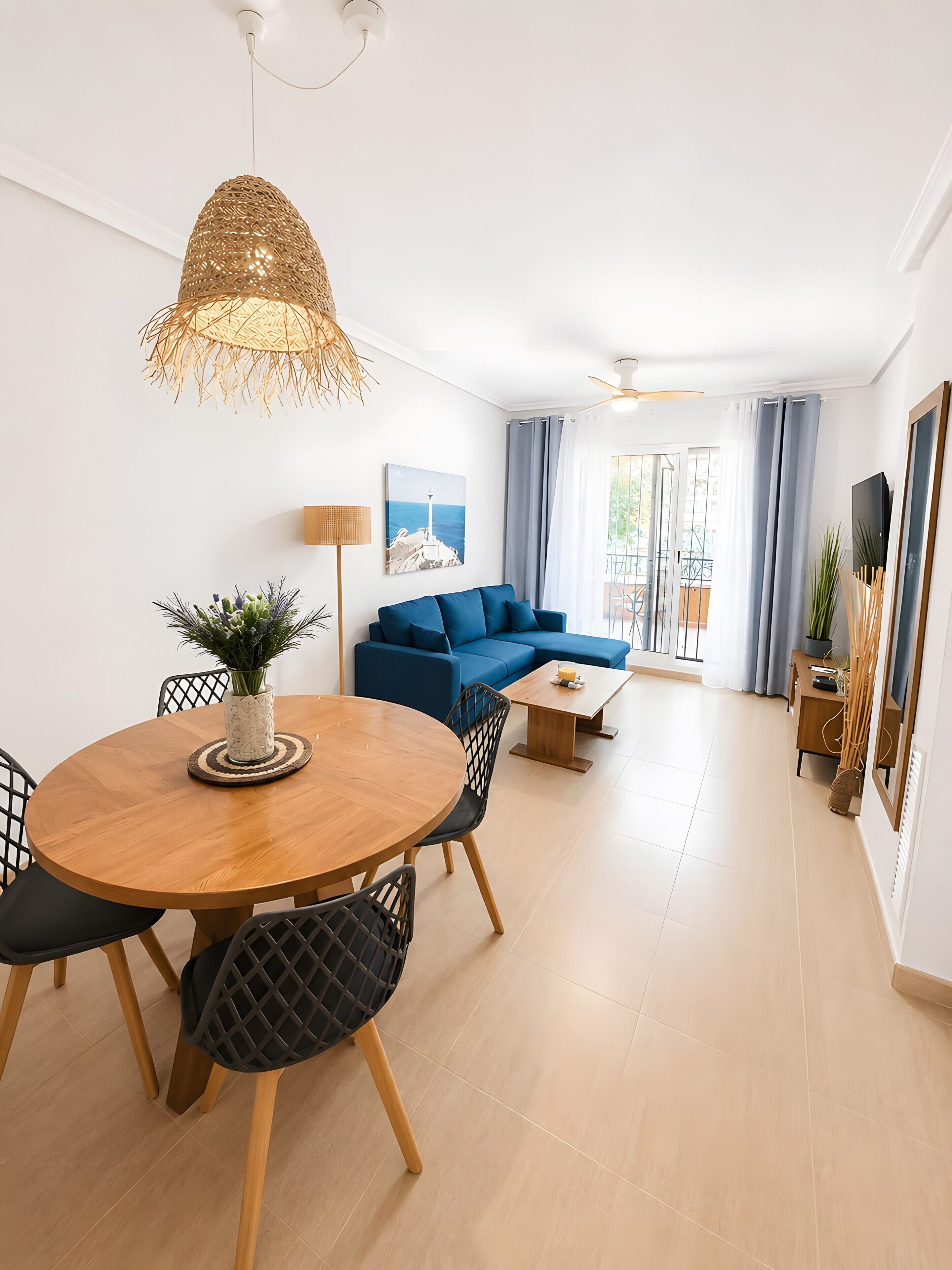 Una sala moderna con una mesa redonda de madera, un sofá azul y una lámpara colgante de fibra.