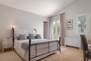 A bedroom with a bed, bedside tables, a chair, and a window with curtains. - Aelia Villa Aegina, Villa (Aegina)