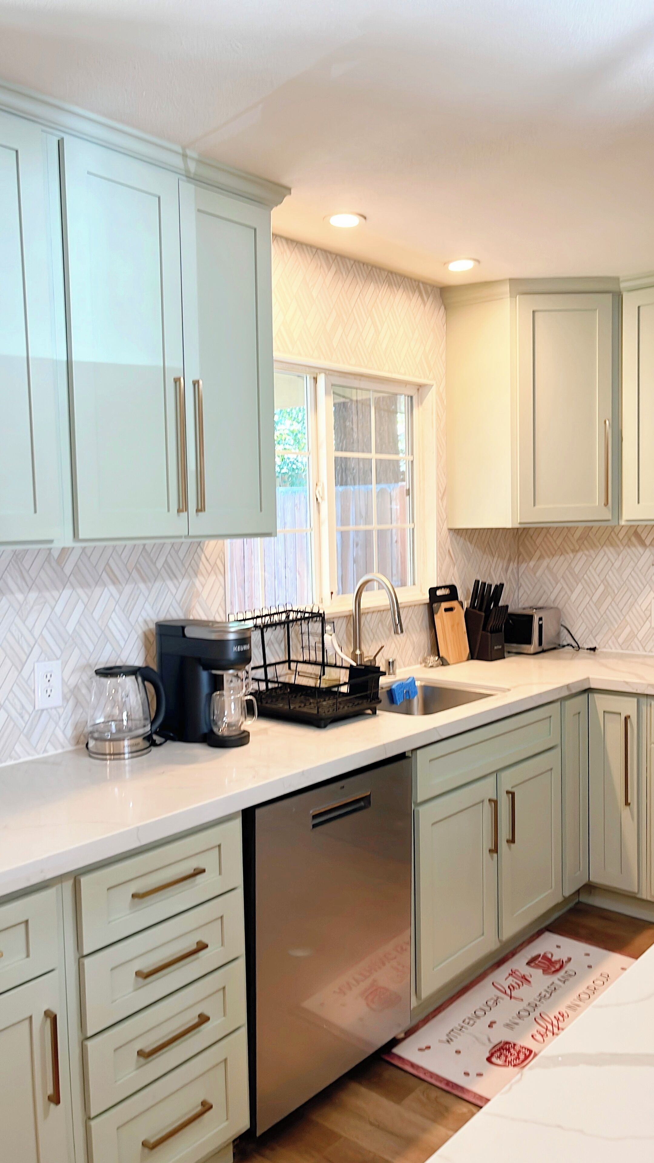 A modern kitchen with light-colored cabinets, a dishwasher, a coffee maker, and a toaster.