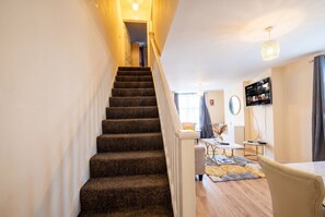 A staircase leading to a living area with a flat-screen TV mounted on the wall. - 3-Bed Townhouse Sleeps 5 · Walk to Designer Outlet & STEAM Museum (Swindon)
