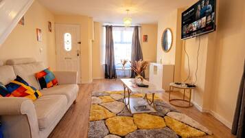 Ein Wohnzimmer mit einer Couch, einem Couchtisch und einem Fernseher, der eine Netflix-Oberfläche zeigt.