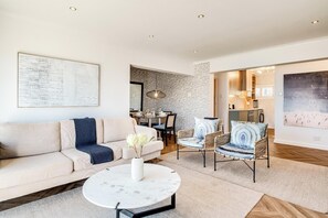 Ein stilvolles Wohnzimmer mit einer Couch, einem runden Couchtisch und zwei Korbstühlen.