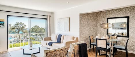 Una sala de estar moderna con un sofá, sillas, una mesa de comedor y un balcón con vistas.