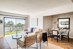 Ein modernes Wohnzimmer mit Sofa, Sesseln, Esstisch und einem Balkon mit Blick.