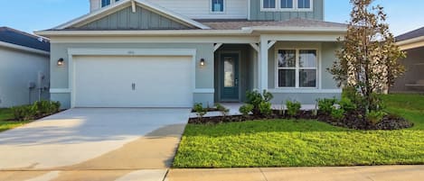 A two-story residential house with a garage, a front porch, and a well-maintained lawn.