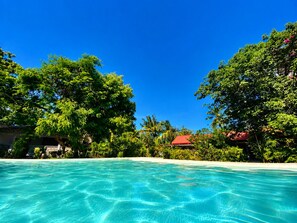 A clear blue pool surrounded by lush greenery and a red-roofed building. - Baobab Garden Studio with pool Watamu (Watamu)
