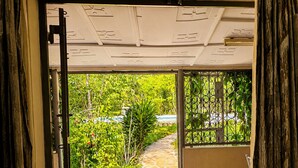An open doorway leading to a tiled patio with a view of a garden and a pool. - Baobab Garden Studio with pool Watamu (Watamu)
