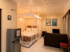 Ein Hotelzimmer mit Himmelbett, Fernseher, Sofa und kleinem Tisch.