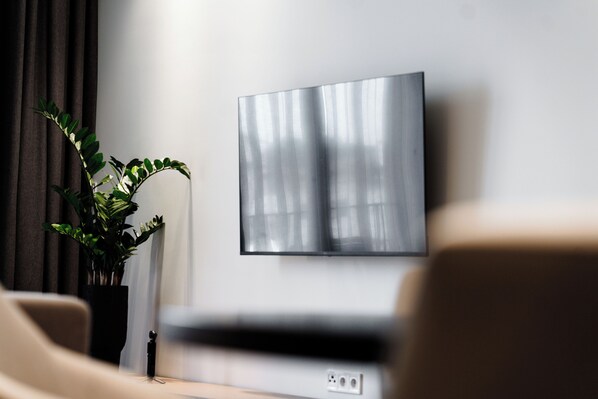 A modern living room with a flat-screen TV mounted on the wall, a potted plant, and a sofa. - ICON RESIDENCES Douala (Douala)