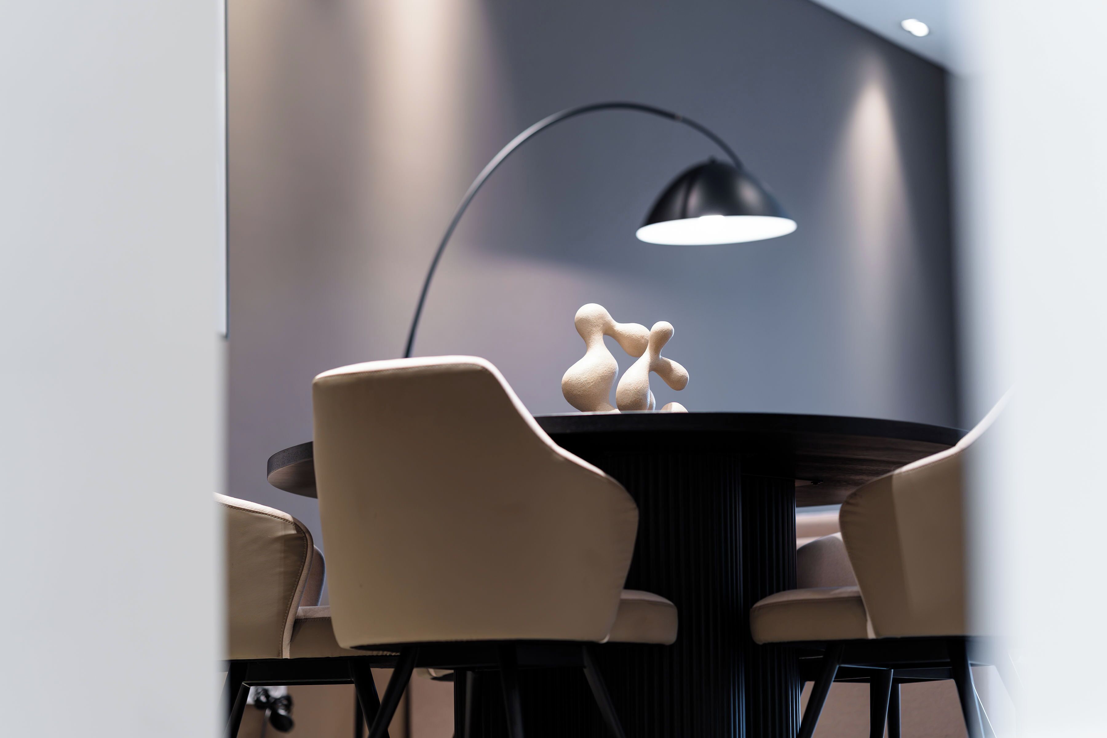 Un comedor moderno con una mesa redonda, cuatro sillas y una escultura llamativa como elemento central.