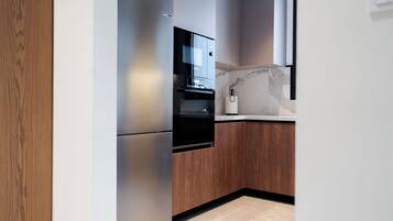 A modern kitchen with a built-in oven, a microwave, and a wooden cabinet.
