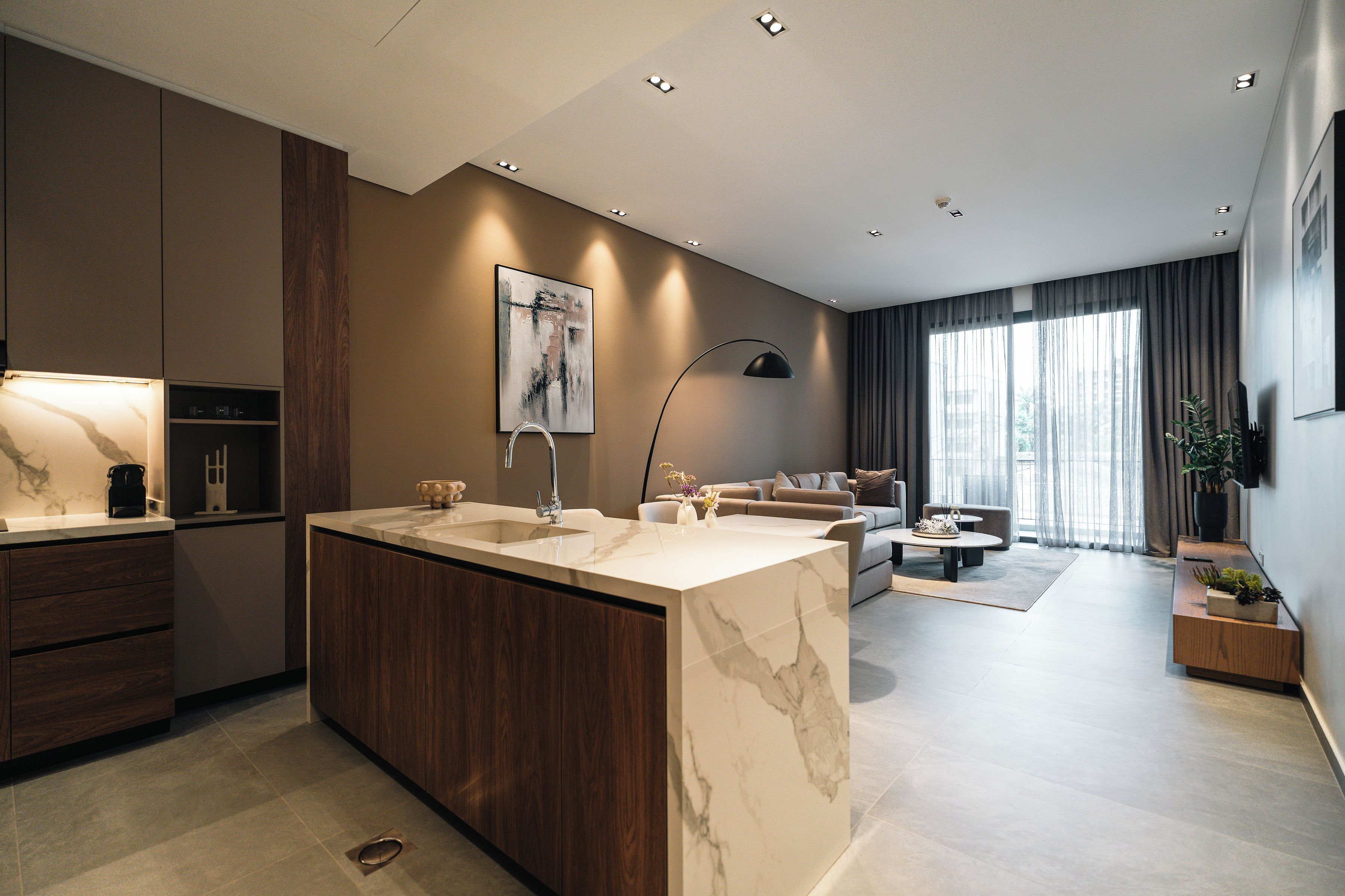 A modern kitchen with a marble island, built-in appliances, and a dining area with a sofa and coffee table.