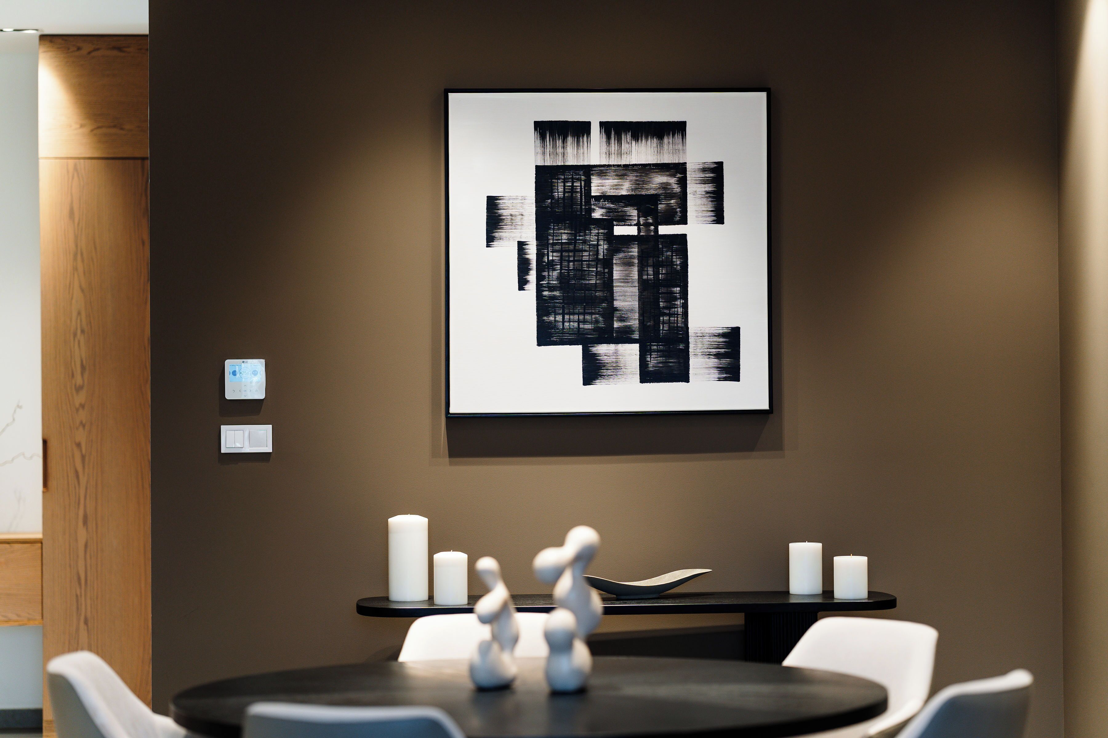 Una sala de conferencias moderna con una mesa redonda, sillas blancas y un cuadro abstracto en blanco y negro minimalista en la pared.