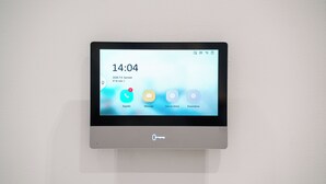 Pantalla digital en la pared que muestra la hora, 14:04, la fecha y el número de habitación.