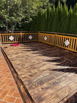 A wooden deck with a brick border, surrounded by a wooden fence with diamond-shaped cutouts.