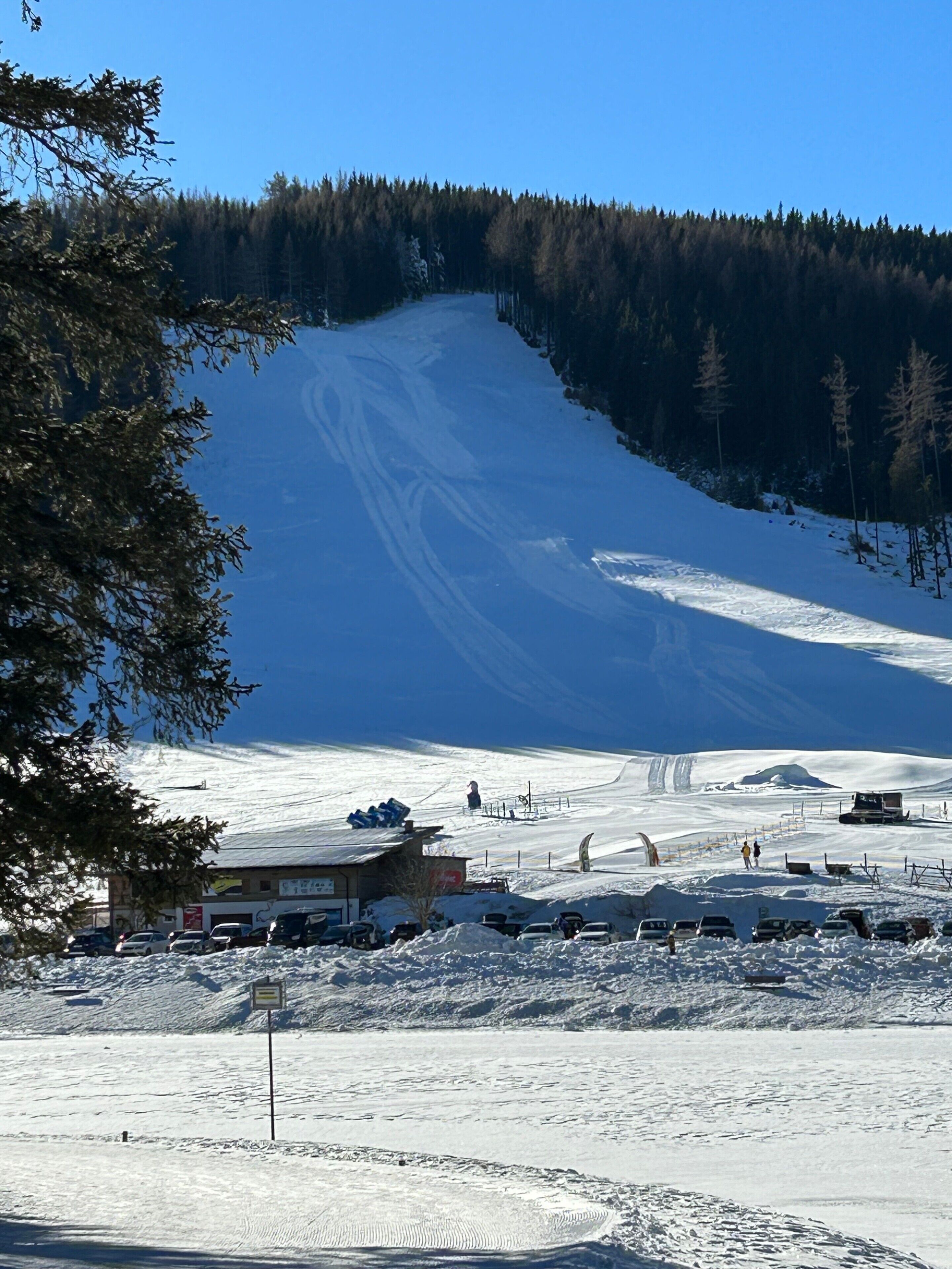 A ski resort with a ski lift, a parking area, and a mountain in the background.
