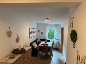 A compact living space with a dining area, a sofa, and a small kitchen. - Holiday Home 'Haus Leiner' with Mountain View, Shared Terrace and Wi-Fi (Baierdorf-Umgebung)