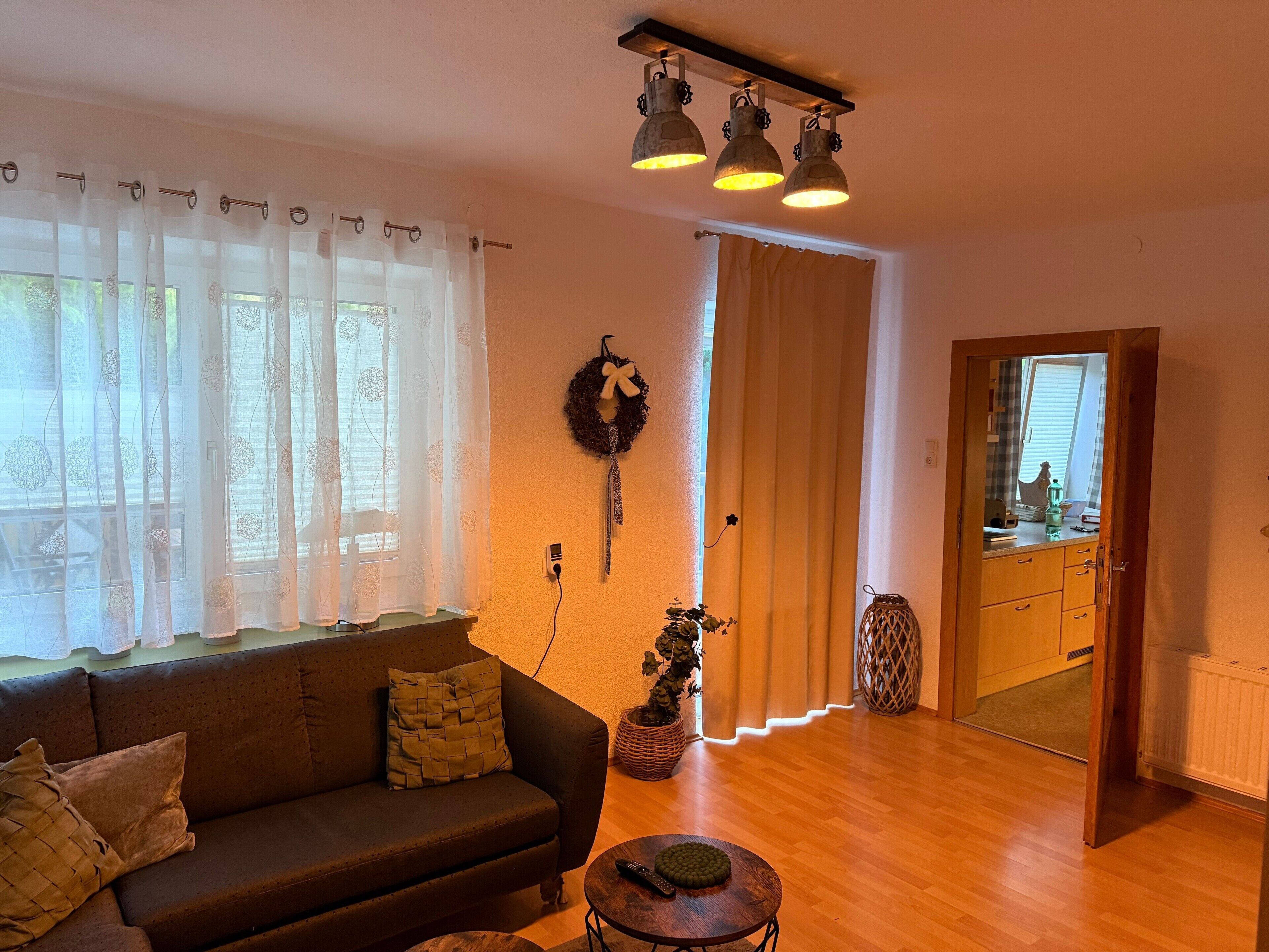 A living room with a sofa, a small round table, and a mirror reflecting a window.