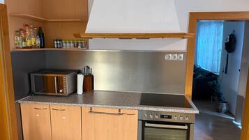 A kitchen with wooden cabinets, a microwave, a stove, and a range hood.