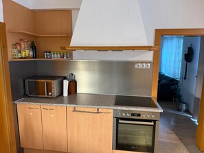 A kitchen with wooden cabinets, a microwave, a stove, and a range hood. - Holiday Home 'Haus Leiner' with Mountain View, Shared Terrace and Wi-Fi (Baierdorf-Umgebung)