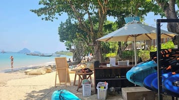 Un paisaje de playa con un kayak, una mesa con sillas y una sombrilla.