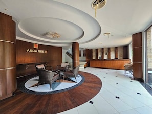 A hotel lobby with a reception desk, seating area, and a staircase.