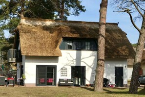 A thatched-roof building with a white facade, large windows, and a door. - My Little Zanzibar 2 (Zirchow)
