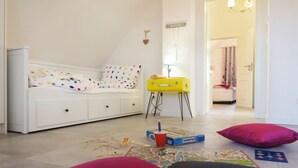 Una habitación infantil con una cama, una maleta amarilla y juegos de mesa.