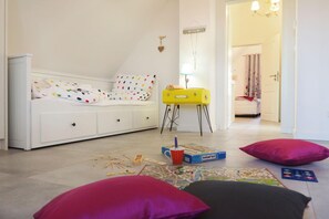 A child's bedroom with a bed, a yellow suitcase, and board games. - My Little Zanzibar 2 (Zirchow)