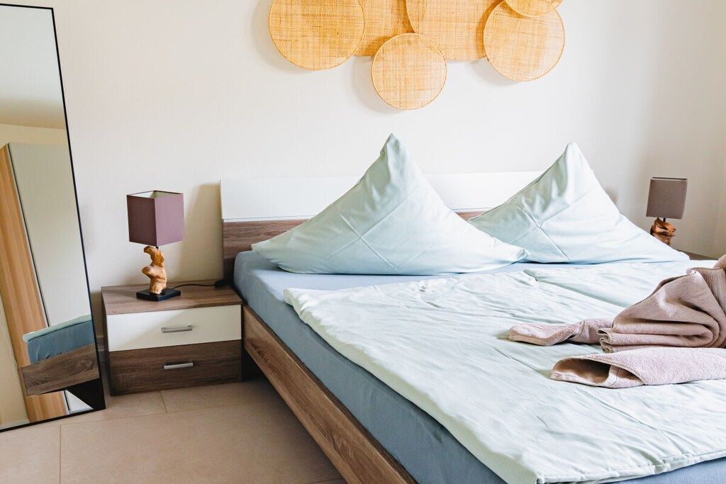 Un dormitorio con cama, mesitas de noche, un espejo y decoración en la pared.