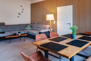 A modern living room with a sectional sofa, a wooden coffee table, and a dining area with a large table and chairs.