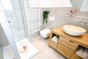 Ein modernes Badezimmer mit Duschkabine aus Glas, einem Holzwaschtisch mit großzügigem Becken und einer Toilette.