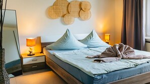 A bedroom with a bed, bedside tables, a mirror, and wall decor. - Holiday apartment with 2 bedrooms (Warnemünde)