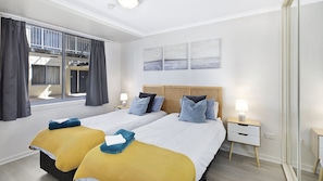 A hotel room with a large bed, two bedside tables, a window with curtains, and artwork on the wall. - NESUTO 408 - Waterview Apartment by HolidayCo. (Unknown)
