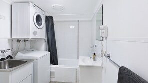 A compact, modern bathroom with a built-in washing machine, a shower area, a sink, and a toilet. - NESUTO 408 - Waterview Apartment by HolidayCo. (Unknown)