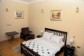 Een slaapkamer met een bed, een stoel, een bureau en twee wandlampen.