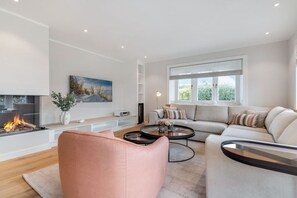 A modern living room with a fireplace, a sofa set, a coffee table, and a large window. - Bals Horsatal 15b / Rüm Hart (Wenningstedt)