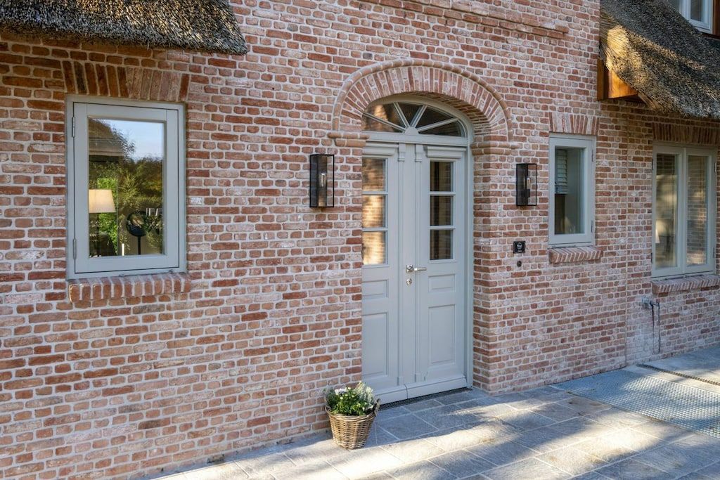 A brick building with a white door, a window, and a small basket with plants.