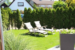 A garden with two lounge chairs, a hedge, and a building in the background. - Holiday apartment with 1 bedroom (Grömitz)