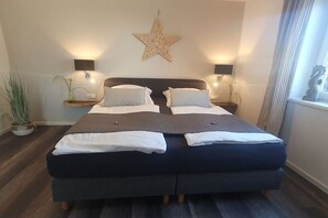 Ein Doppelbett mit dunklem Kopfteil, zwei Nachttische mit Lampen, eine Stern-Dekoration an der Wand und ein Blumentopf.