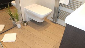 Une salle de bain avec des toilettes, un porte-serviettes et une plante.