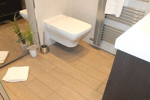 Een badkamer met een toilet, een handdoekhouder en een plant.