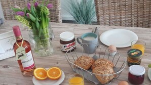 Ein Frühstückstisch mit Brot, Eiern, Saft und Beilagen.