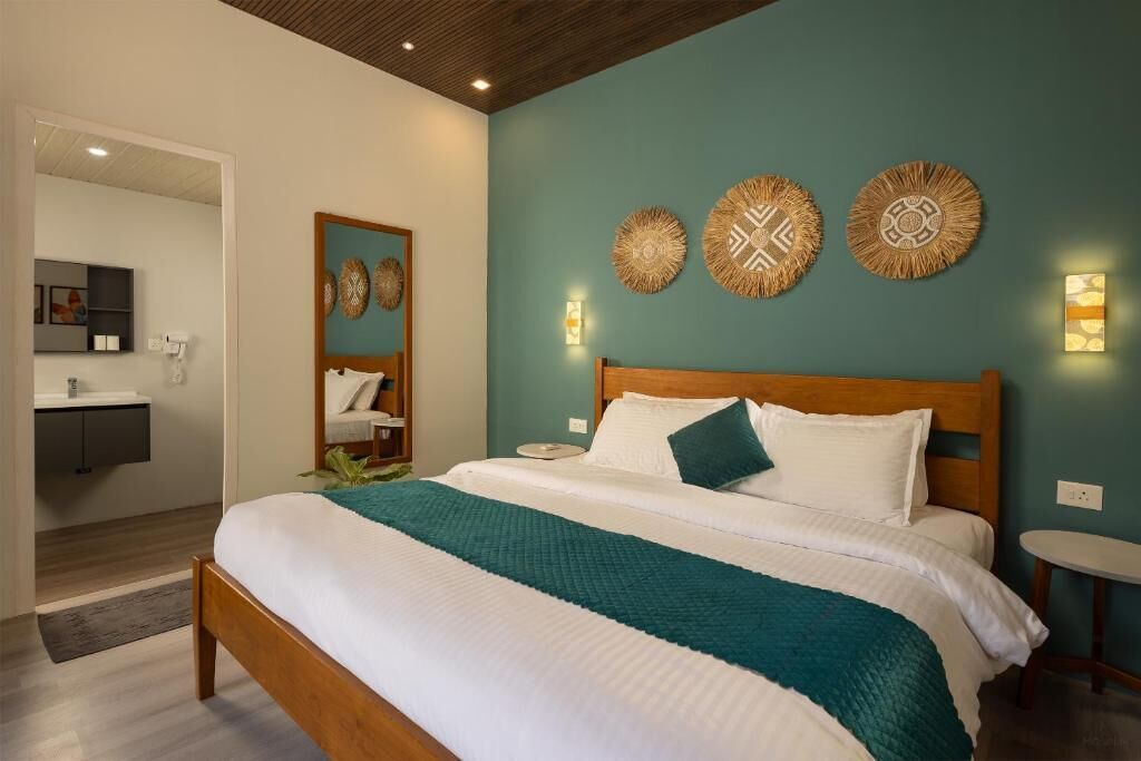 A bedroom with a wooden bed, teal bedding, a mirror, and decorative wall art.